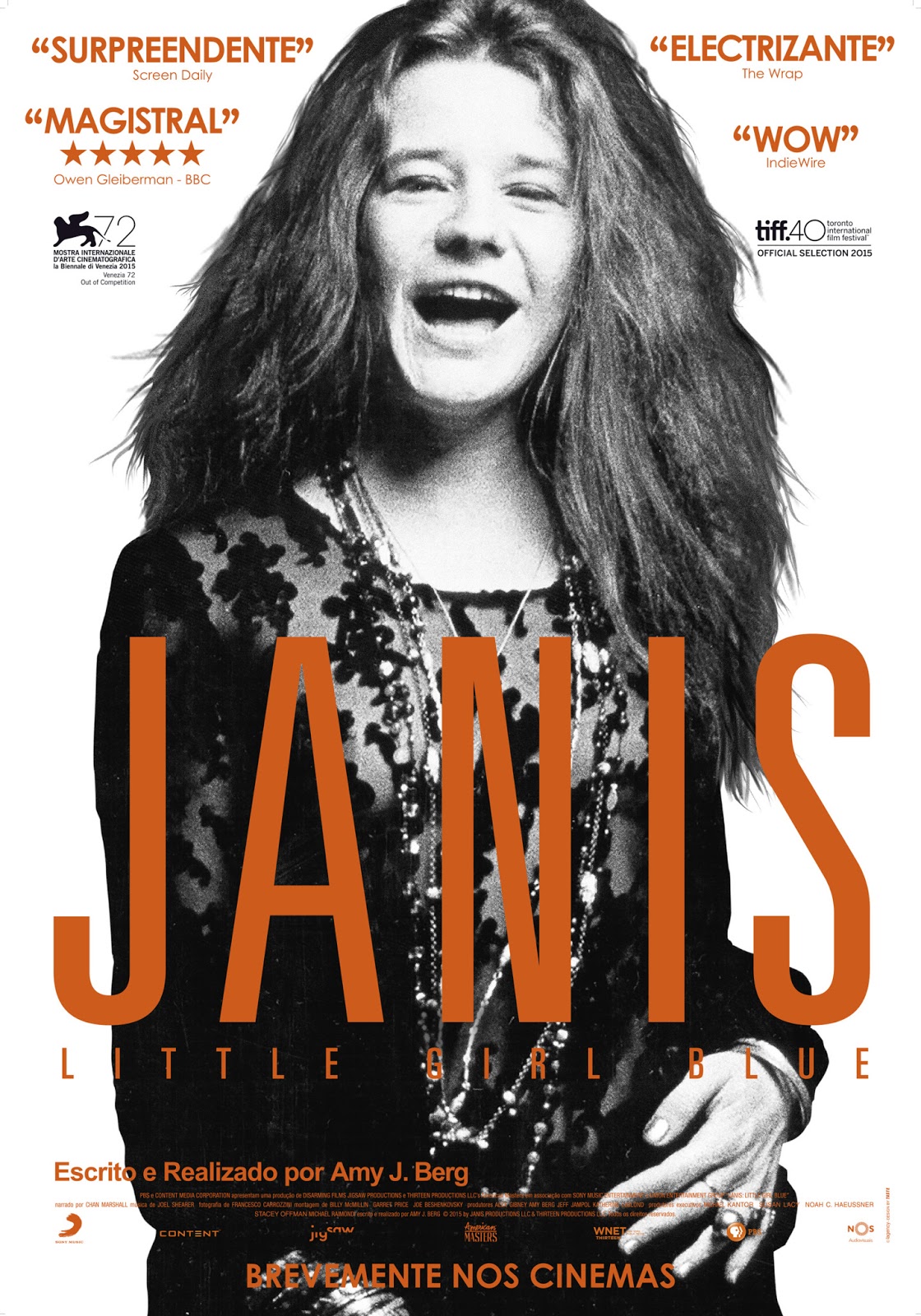 Janis Joplin está em pé, virada para a câmera e sorrindo. Em frente ao seu corpo está o título do filme Janis, Little Girl Blue.