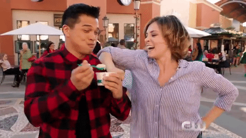 Gif em que Josh está tomando sorvete e dá um pouco para Rebecca. Ela toma o sorvete e finge mordê-lo.