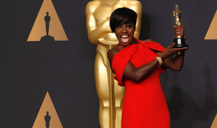 Viola Davis mostra sua estatueta do Oscar e sorri.